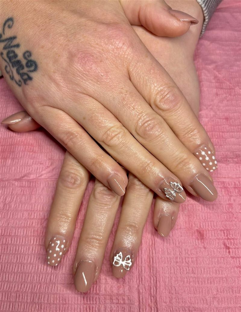 Nude gel nails with white polka dots and 3D silver bows